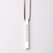 Silver necklace with a bar pendant engraved with 'BRAVE AS FUCK' on a white background