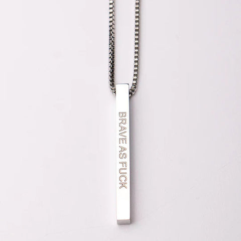 Silver necklace with a bar pendant engraved with 'BRAVE AS FUCK' on a white background