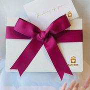 Gift box with a rose colour ribbon and 'Care Box' logo on a light background