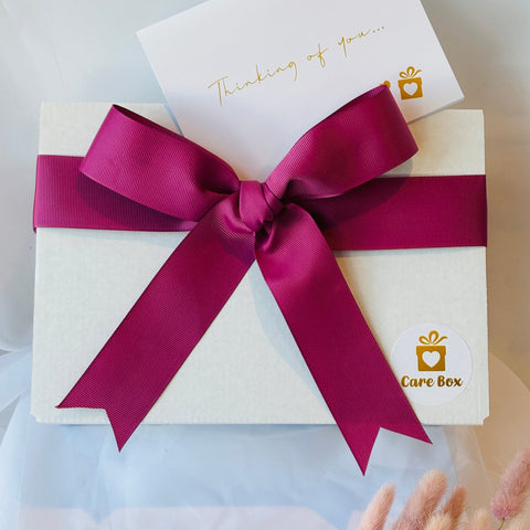 Gift box with a rose colour ribbon and 'Care Box' logo on a light background