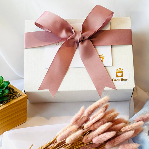White gift box with a pink ribbon on a white surface with decorative elements.