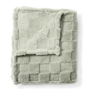 Folded green textured blanket on a white background