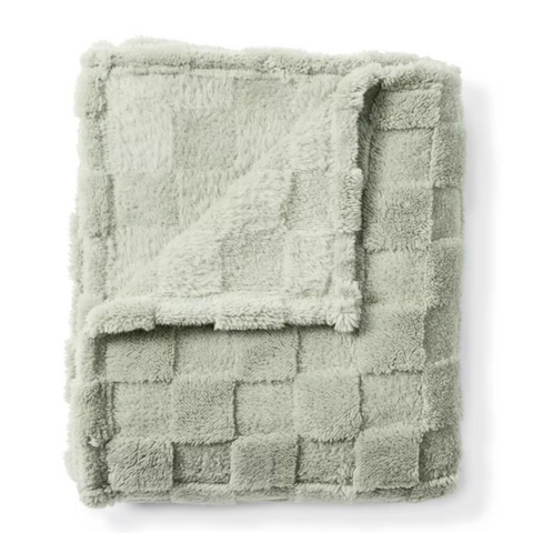 Folded green textured blanket on a white background