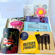 Collection of snacks and treats including Buttery Fingers shortbread, coconut ice, and other packaged goods on a white background.