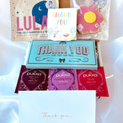 Assorted items including a 'Thank You' card, Lula self-warming eye mask, and Pukka tea bags on a white background.