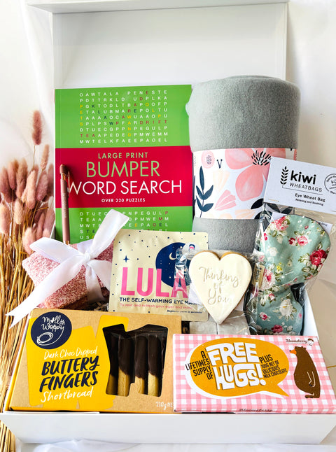 Gift basket with various items including a word search book, heart-shaped cookie, and butterscotch fingers.